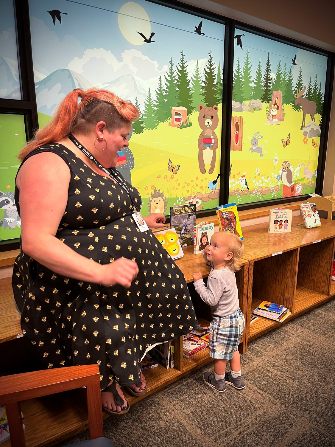 Lacey Timberland Librarian Kerry Martin helps young patron Logan Whorley, age 1, as he engages with picture books in the children's section of the library.